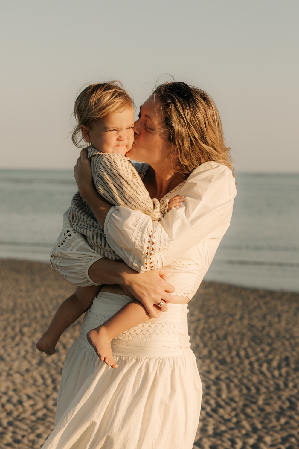 Coco holding her child on the beach at golden hour